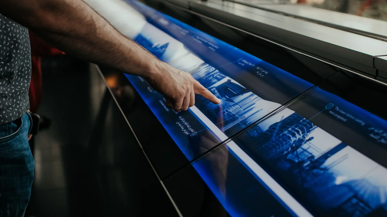 Close-up of a person interacting with a touchscreen display in a modern environment.