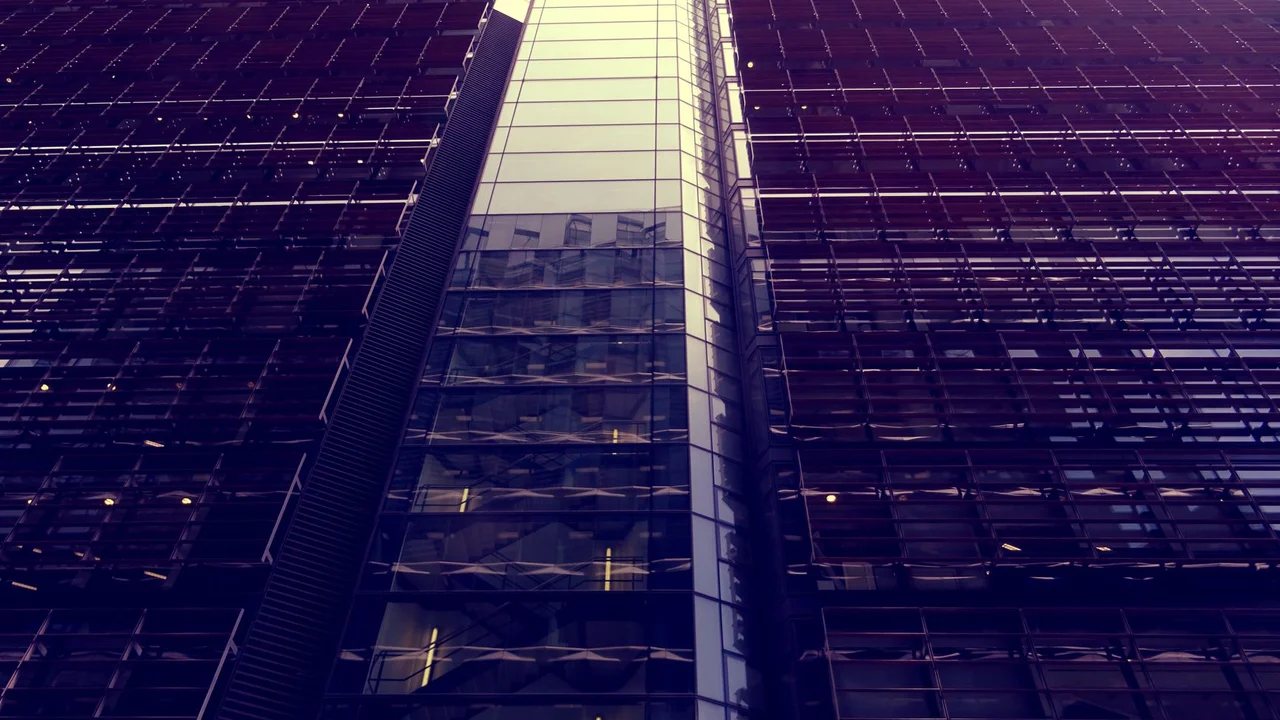 Low angle view of a modern skyscraper with reflective glass facade and urban architecture.