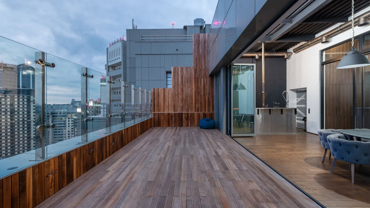Empty spacious terrace with wooden floor and walls placed in modern apartment in cloudy day