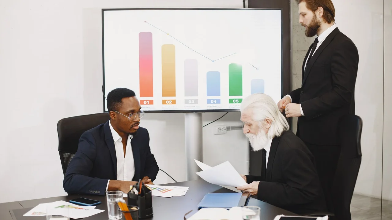 Three businessmen discussing financial data in a modern office setting with charts.