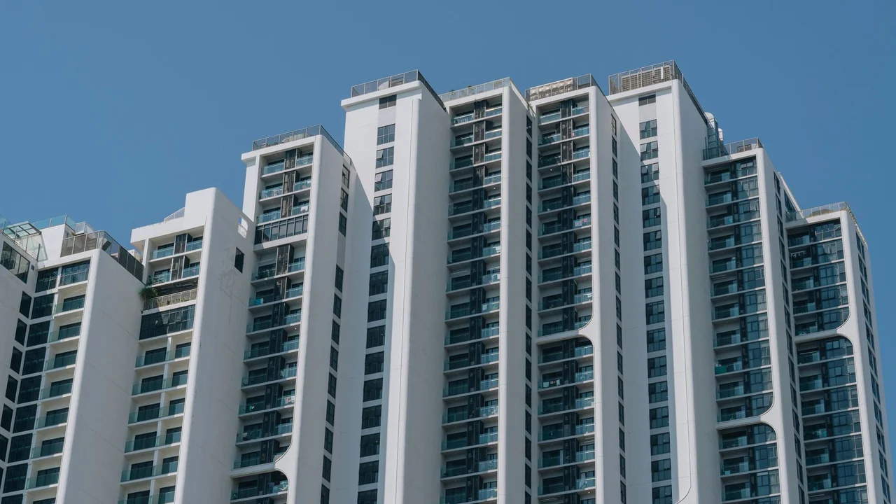 Contemporary high-rise apartment building with unique design and glass facades against a clear blue sky.