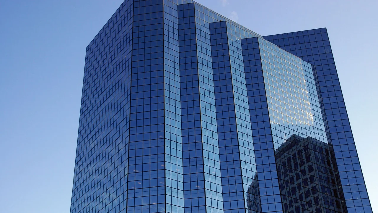 A modern skyscraper with reflective glass facade under a clear blue sky.