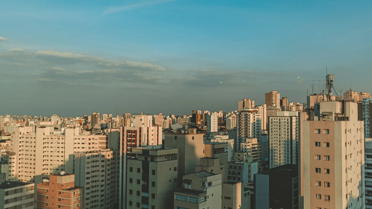 Aerial view of a dense city skyline at dusk with modern skyscrapers and a clear sky.