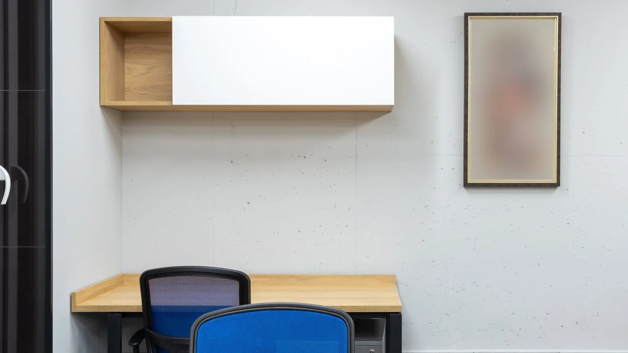 Wooden tables and blue office chairs placed in modern workplace with shelves on wall