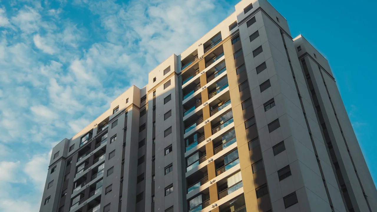 View of a modern residential skyscraper with a clear blue sky backdrop, shot from a low angle.