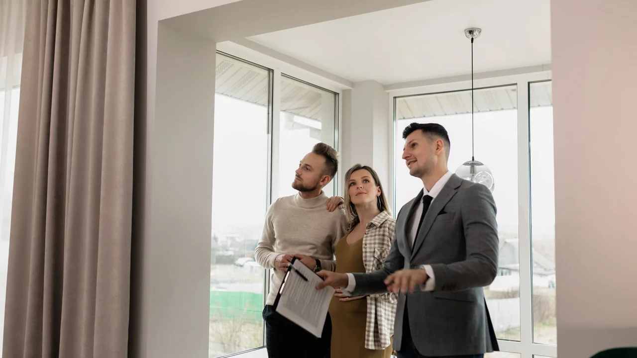 A real estate agent showing a modern home to a young couple during a daytime viewing.
