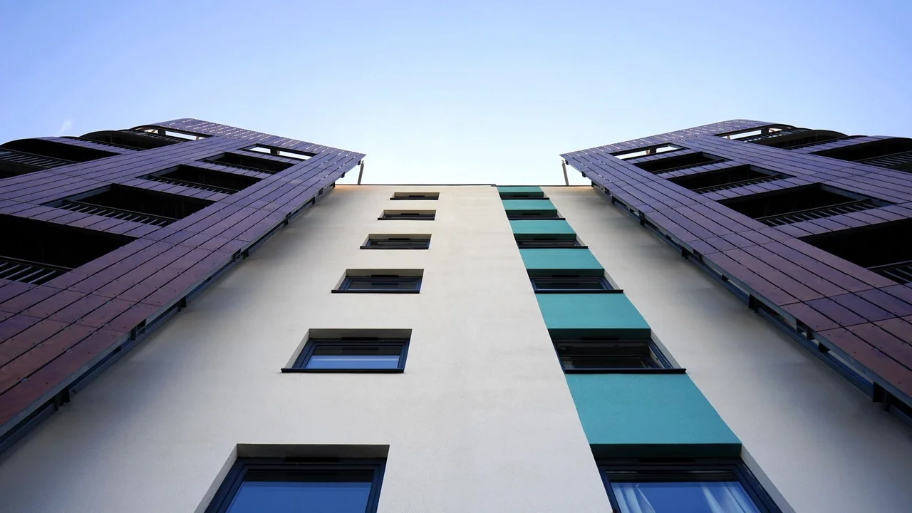 Low angle view of a modern skyscraper with glass facade against a clear sky.