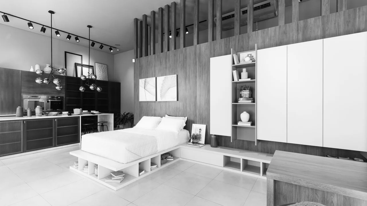 Black and white image of a modern minimalist bedroom with sleek furniture and lighting.