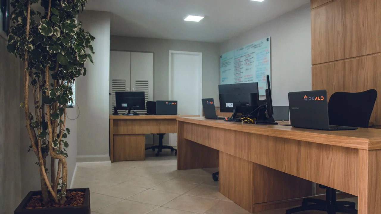Contemporary office space featuring desks with computers and revolving chairs.