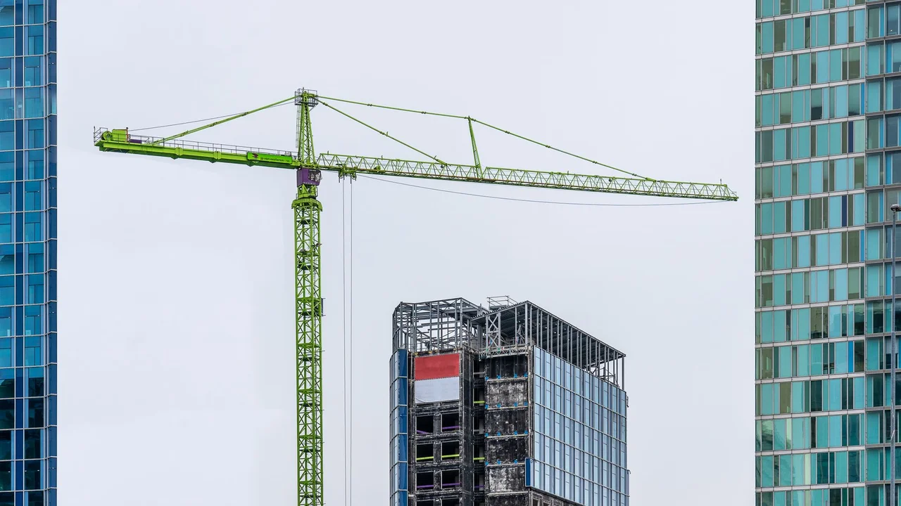 High-rise building under construction with crane and modern facades, showcasing urban architecture.