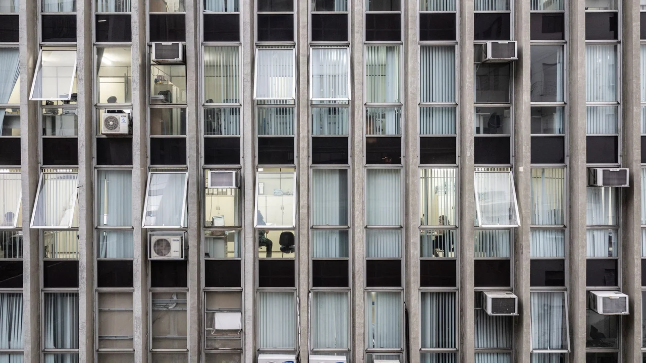 A detailed view of an office building's facade with glass windows and air conditioners in São Paulo.