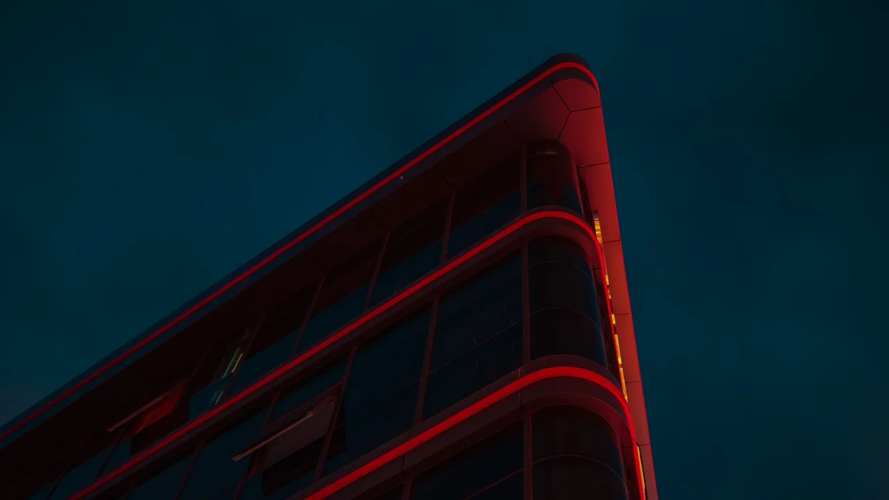 A dramatic view of a modern building with red lighting against a night sky, captured in Güzelyurt.