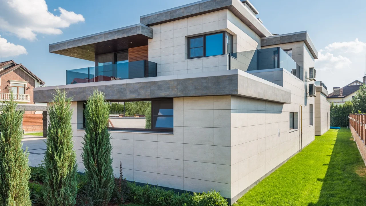 Contemporary two-story house with clean lines surrounded by green grass and blue sky.