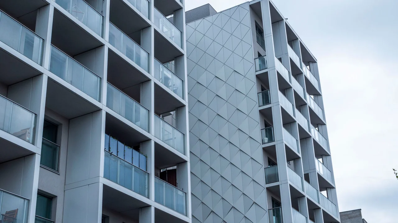 Contemporary glass facade of a city apartment building under a cloudy sky.